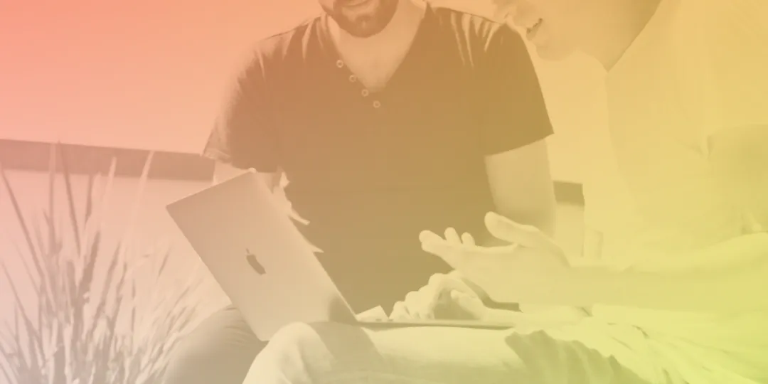 Two people chatting and looking at a laptop