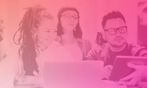 Image shows a group of people gathered around a desk. One person is holding an iPad and showing what's on it to the group.