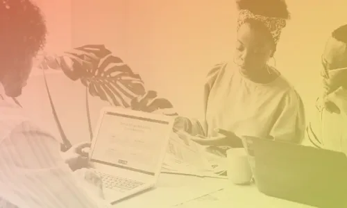 Image of three people in an office setting with laptops in front of them.