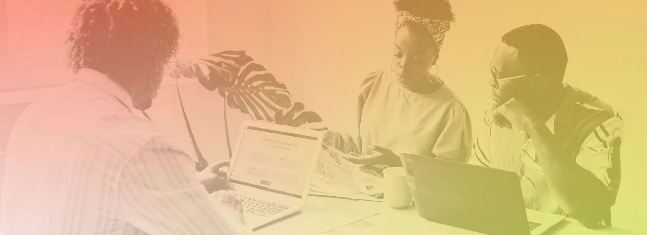 Image of three people in an office setting with laptops in front of them.